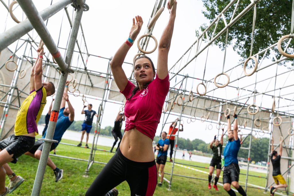 Strong Viking deelneemster die aan ringen hangt. Eten voor het sporten eten obstacle run voeding is belangrijk voor extra energie