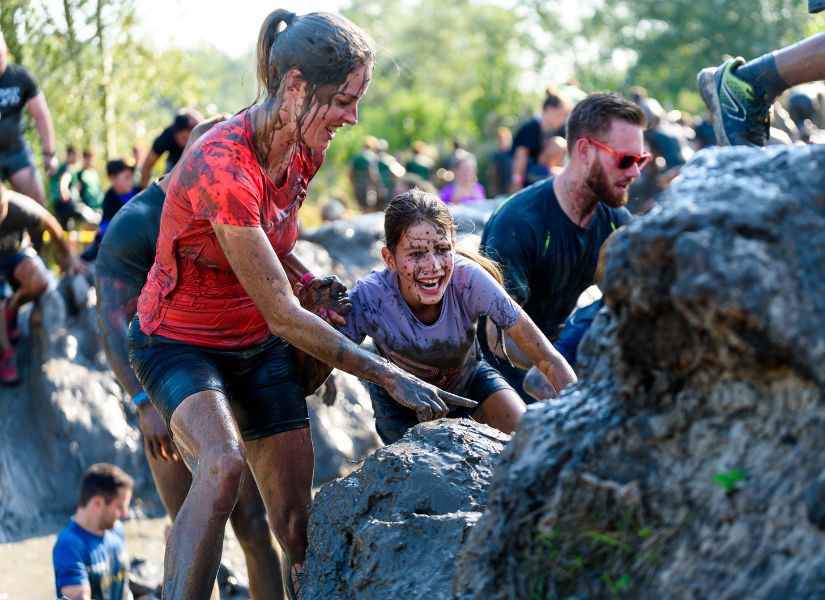 kinderen en ouders klimmen door de modder
