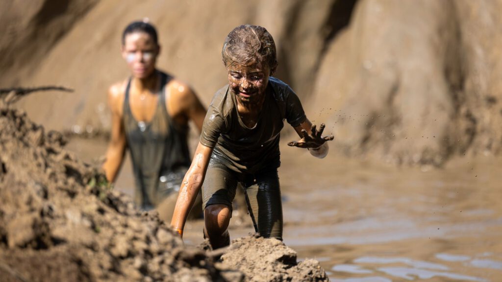 kindje dat door de modder klimt met haar moeder op de achtergrond tijdens de strong viking family run