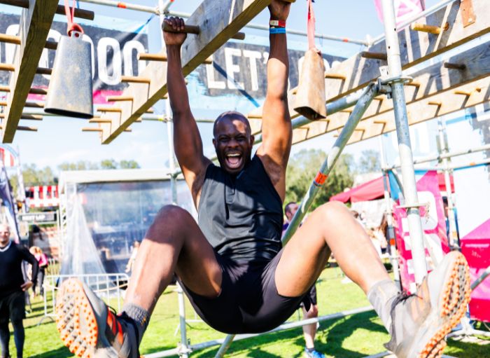 A man laughing while hanging from a climbing frame.