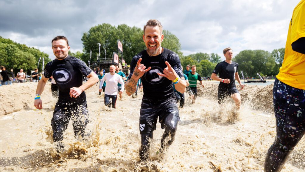 man die lachend door het water rent tijdens de strong viking run
