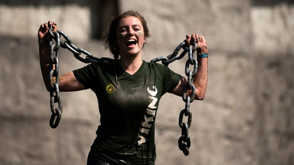 Vrouw tijdens strong viking obstacle run die lachend een ketting draagt