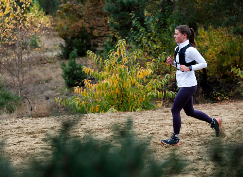 A woman running through the sand during the Strong Viking Trail Run in Wijchen. Running for beginners. Building up running.
